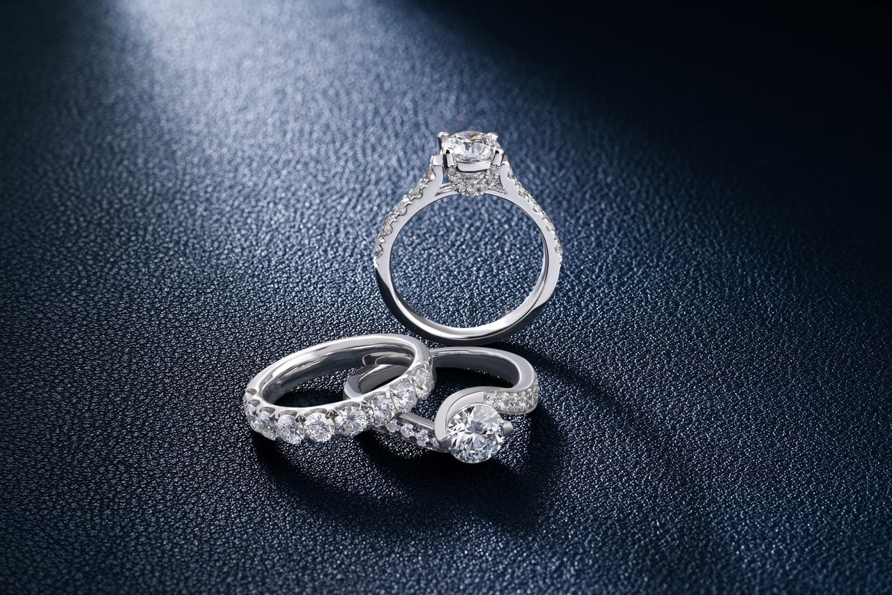 hero-img-02 Close-up of luxurious diamond engagement and wedding rings on a textured surface, showcasing elegance and craftsmanship.