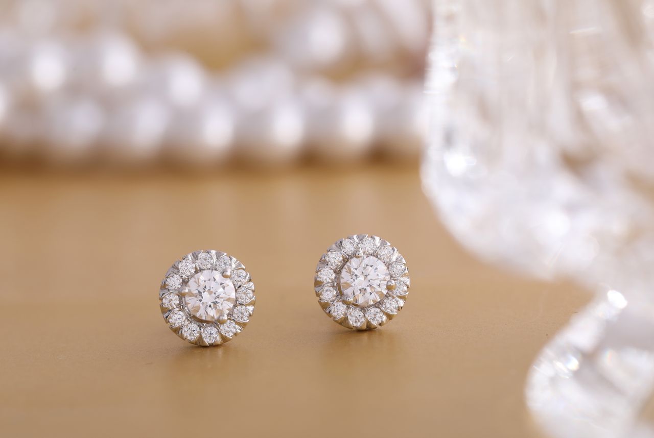 about-01 Close-up of round diamond earrings on a gold background, showcasing luxury and elegance.