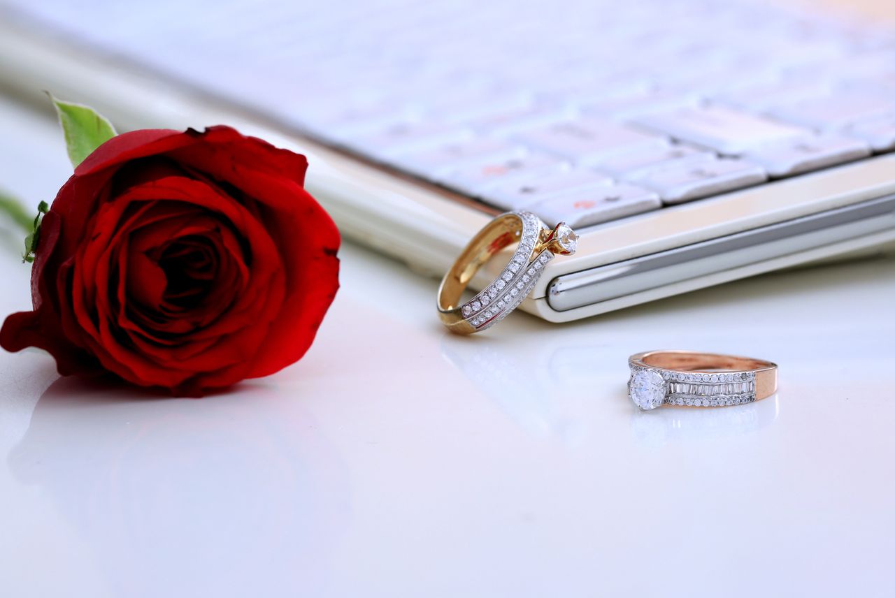 hero-img-01 Elegant diamond rings and a red rose displayed on a clean white surface, symbolizing luxury and romance.