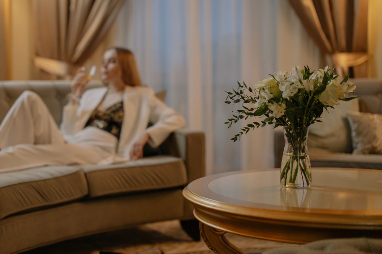 services-03 Luxurious hotel room with white flowers and a woman relaxing, creating a serene atmosphere.
